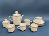 a white tea set with cups and saucers on a blue background