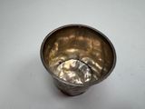 an old silver cup with a handle on a white surface