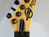 the neck of a yellow electric guitar with black knobs on a white background