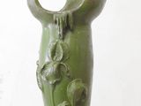 a green vase with flowers on it on a table