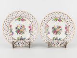 une paire d'assiettes en porcelaine ornées de motifs floraux et bordées d'or