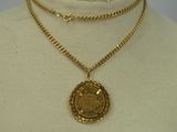 a gold necklace with a coin on a mannequin neck