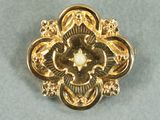 une image d'une broche en or avec une perle au centre