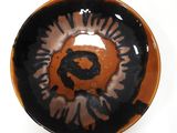 a black and orange bowl with a picture of a bear on it