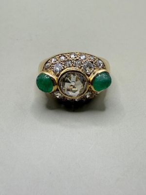 a close up of a diamond and emerald ring on a table