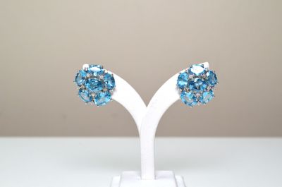 une paire de boucles d'oreilles en cristal bleu posées sur un support blanc, sur une table