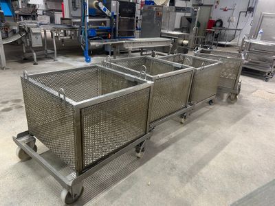 quatre bacs métalliques à roulettes dans une grande pièce