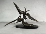 sculpture en bronze représentant deux oiseaux sur un socle noir, sur fond blanc