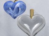 two heart shaped glass pendants with gold accents on a white background
