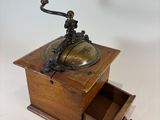 an old fashioned coffee grinder sitting on top of a wooden box