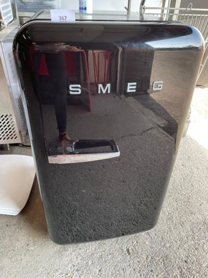 un petit réfrigérateur noir sur lequel est inscrit « sme »