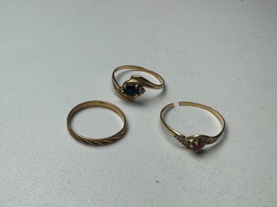 trois bagues en or ornées de grenats, posées sur une table