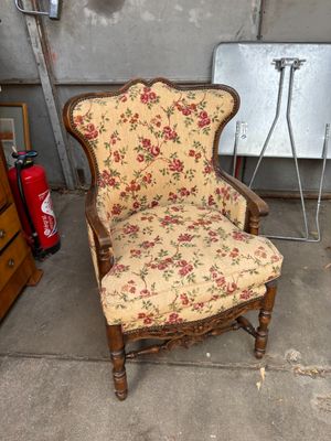 une chaise dont l'assise est recouverte d'un tissu à motifs floraux, dans un garage