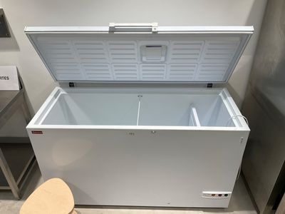 a white chest freezer sitting on top of a counter next to a chair