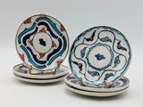 two plates with blue and orange designs on them sitting on a white surface