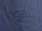 the back of a blue shirt with a picture of a man ' s signature on it