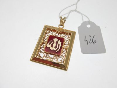 an image of a gold and red pendant with a tag on it