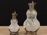 two glass vases sitting on top of a table next to each other