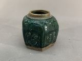 a green vase with a design on the outside of it