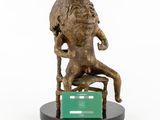 statue of a woman sitting on a chair with a green card