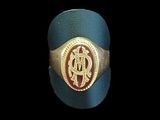 une image représentant une bague dorée et bleue ornée d’un monogramme