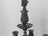 a chandelier that has five candles and a vase on it