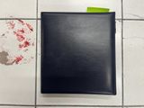 a black folder on the floor next to a yellow post - it