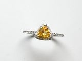 un gros plan d'une bague sertie d'un diamant jaune sur une surface blanche
