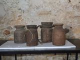 quatre vases posés sur une table devant un mur de briques