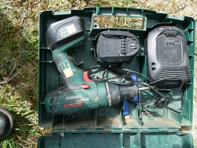 une boîte verte contenant des outils, posée sur l'herbe