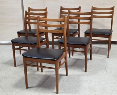 quatre chaises en bois avec des assises en cuir noir dans une pièce