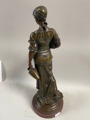 bronze statue of a woman holding a watering pot on a wooden base