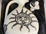 a white vase with a sun design on it in a box