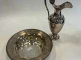 a silver plate and a silver vase on a white table