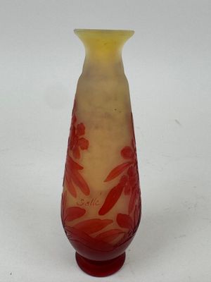 un vase rouge et jaune posé sur une surface blanche