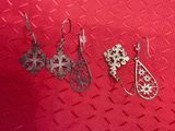 trois paires de boucles d'oreilles posées sur un fond rouge