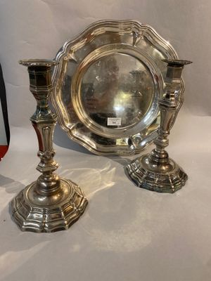 two silver candlesticks and a silver plate on a white background