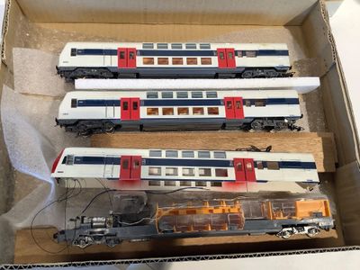 trois trains miniatures dans une boîte posée sur une table