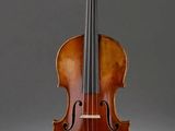 un vieux violon posé sur un chevalet, sur fond gris