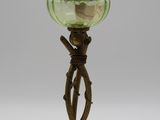 une lampe à huile ancienne en laiton et verre vert, posée sur un trépied