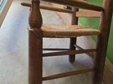 a wooden chair with a woven seat in front of a window