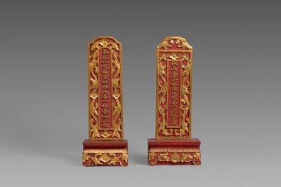 deux serre-livres rouges et dorés posés sur une surface grise