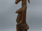 an old wooden statue of a man sitting on a chair