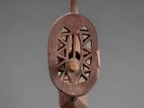 a wooden sculpture of a face on a metal stand