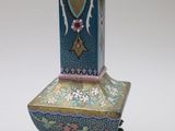 a blue and pink vase sitting on top of a stand