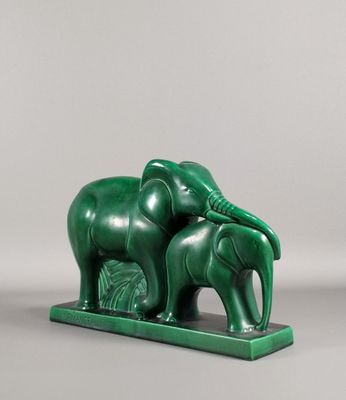 une image représentant une statue d'éléphant verte sur laquelle est perché un éléphanteau