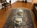 un salon avec un tapis et une table en verre sur laquelle sont posés des crânes
