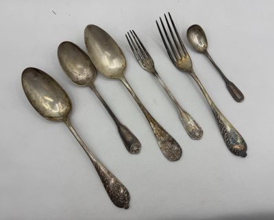 six silver spoons and a fork on a white surface