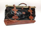 sac de voyage vintage en cuir noir et marron sur fond blanc