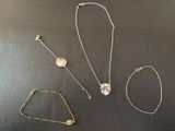 four different necklaces and bracelets on a black surface